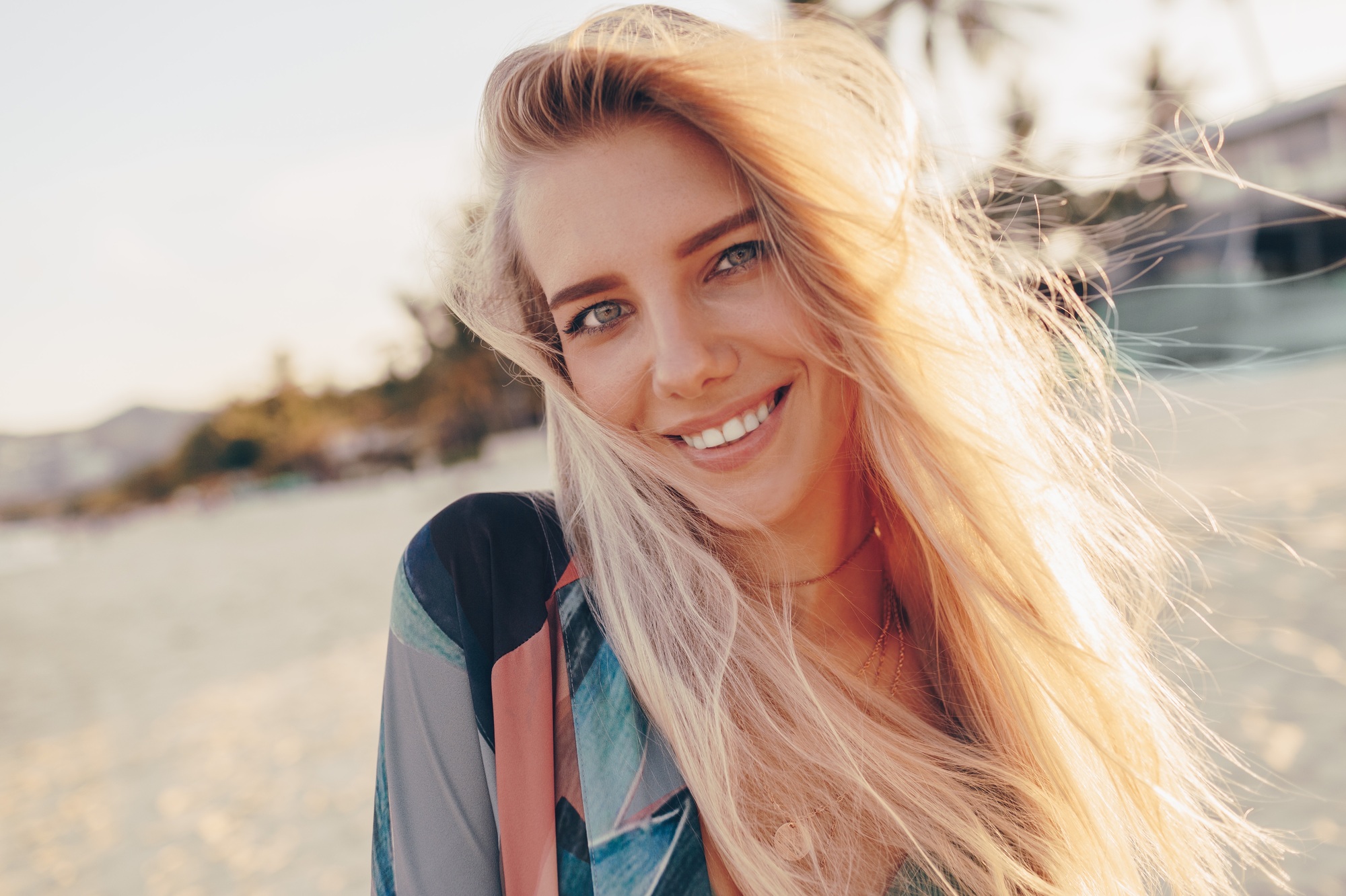 Happy blond woman with perfect smile having fun on sunny beach, looking at camera,