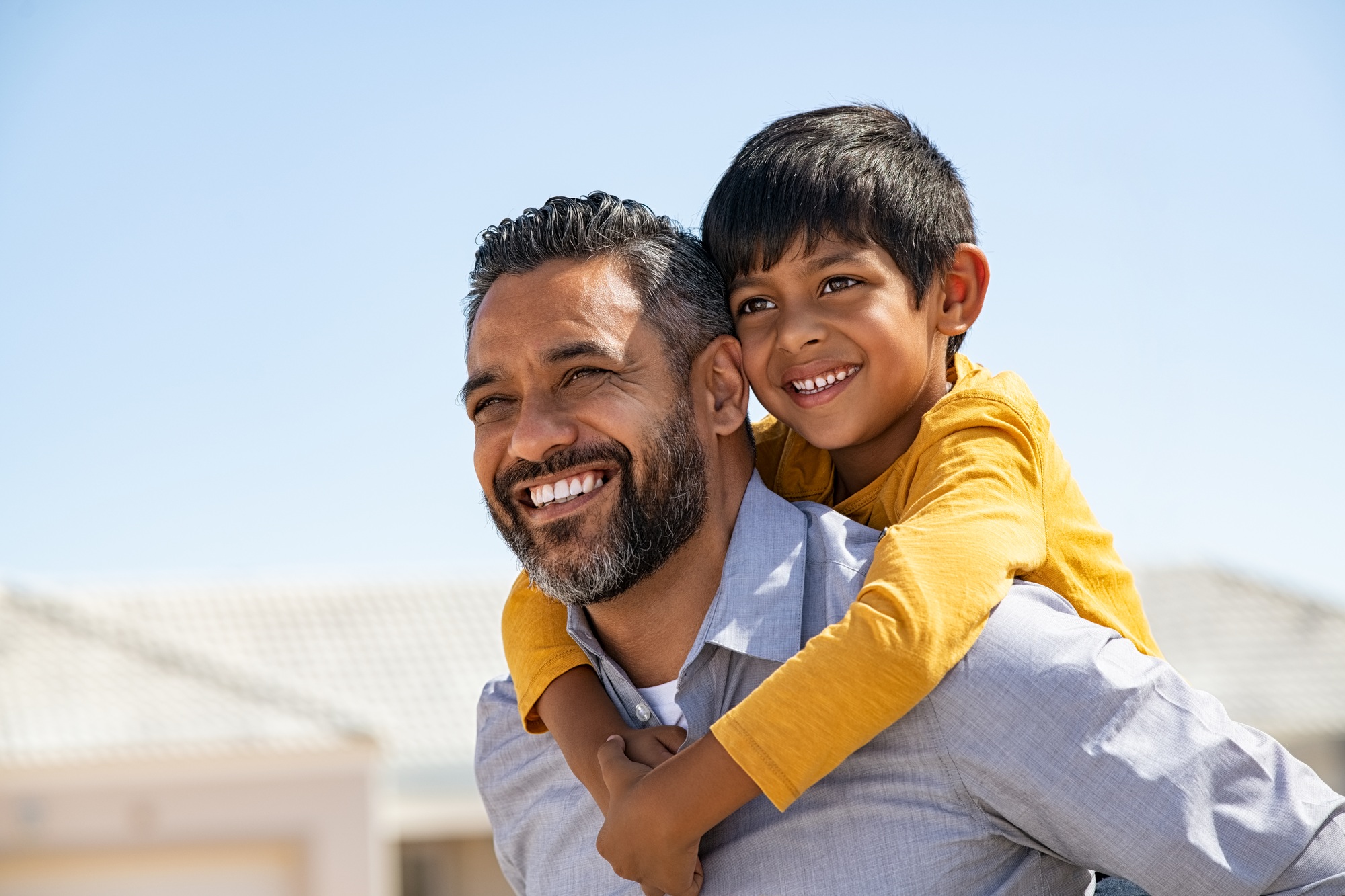 Happy smiling indian father giving son ride on back
