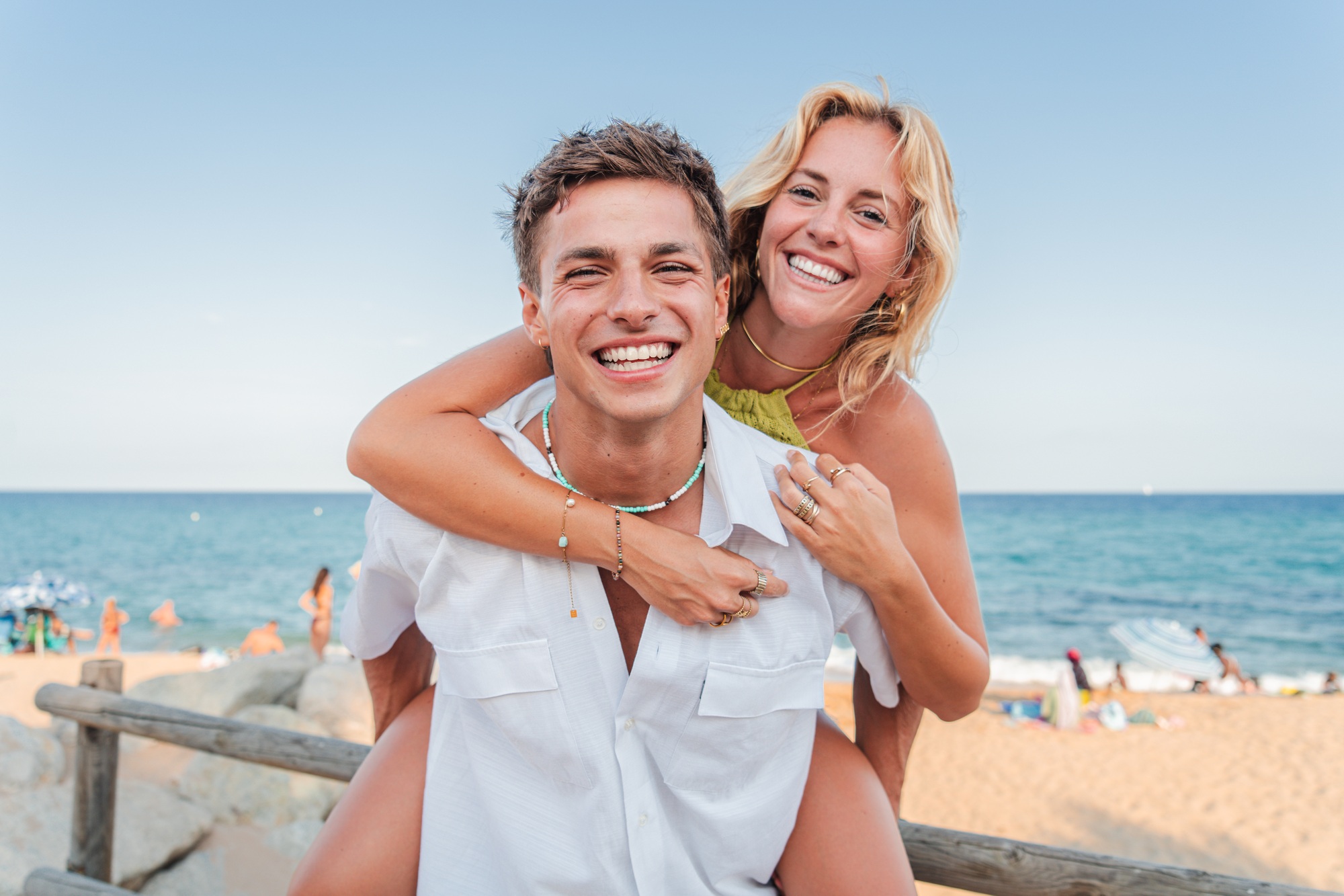 Joyful Young Couple Enjoying a Playful Moment at the Beach with Bright Smiles and Laughter