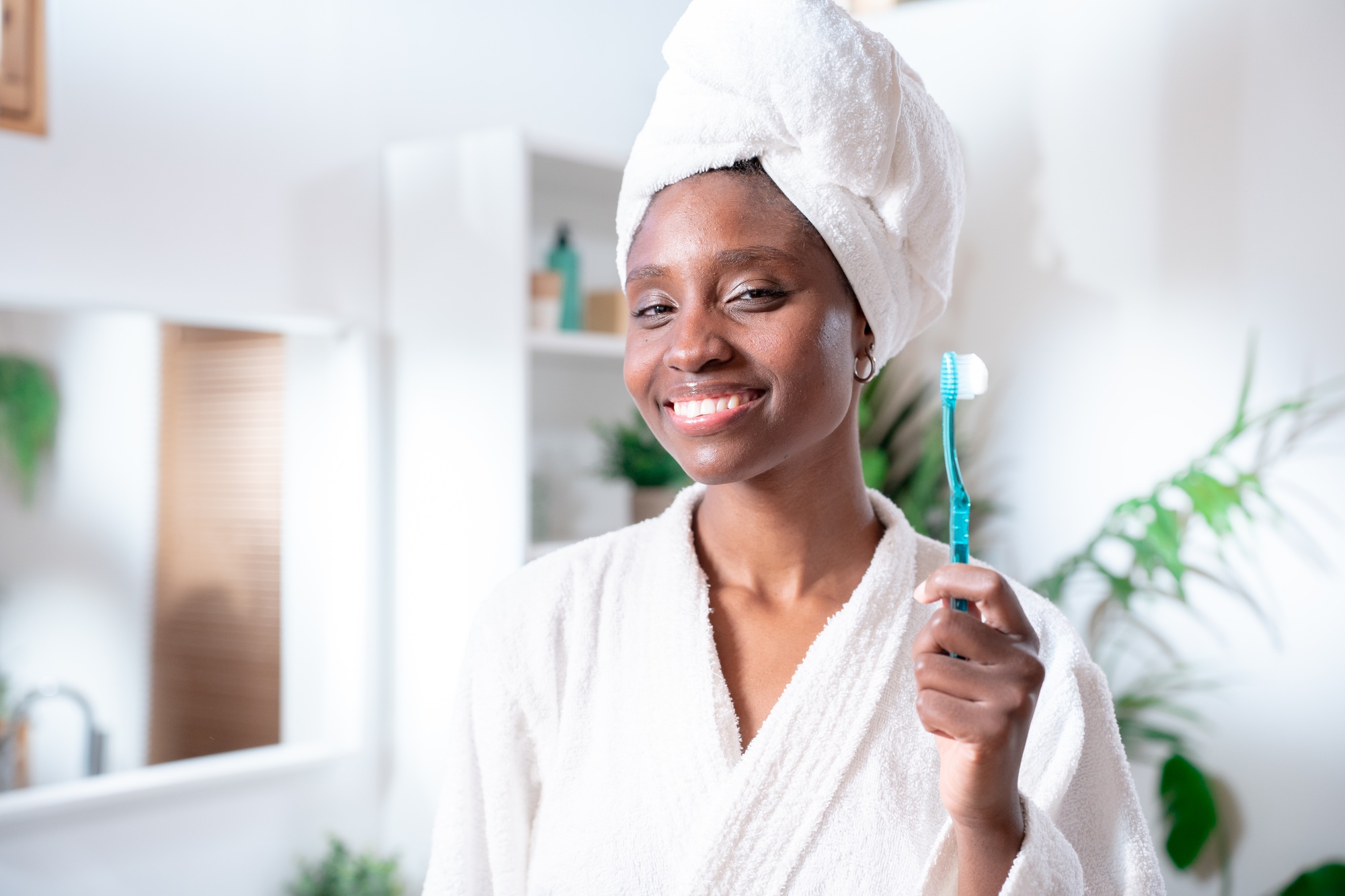 Positive young African American woman holds toothbrush. Perfect smile, cleans teeth.