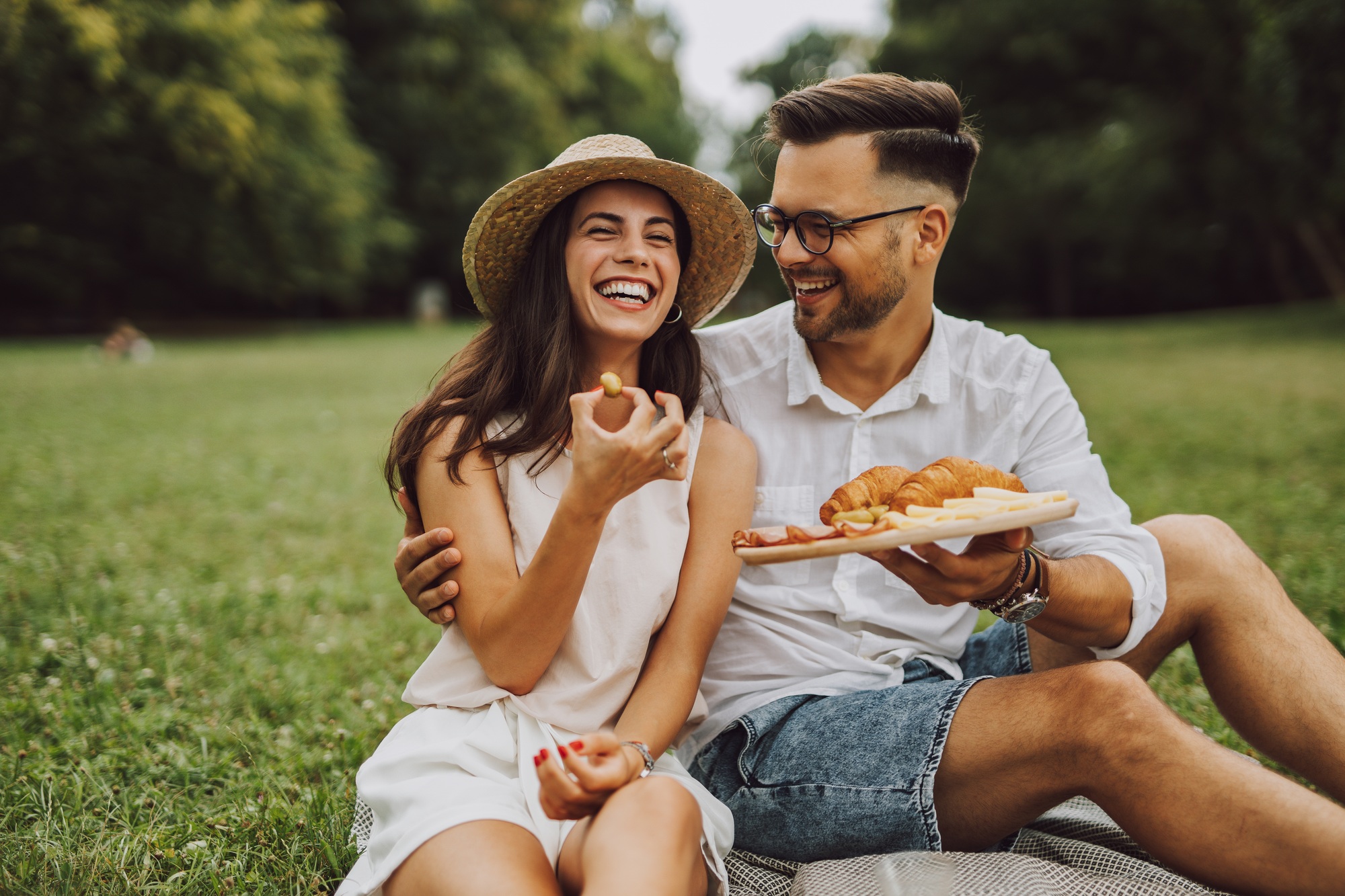 Smiling people sitting on the grass, enjoying themsleves together, during the summertime.