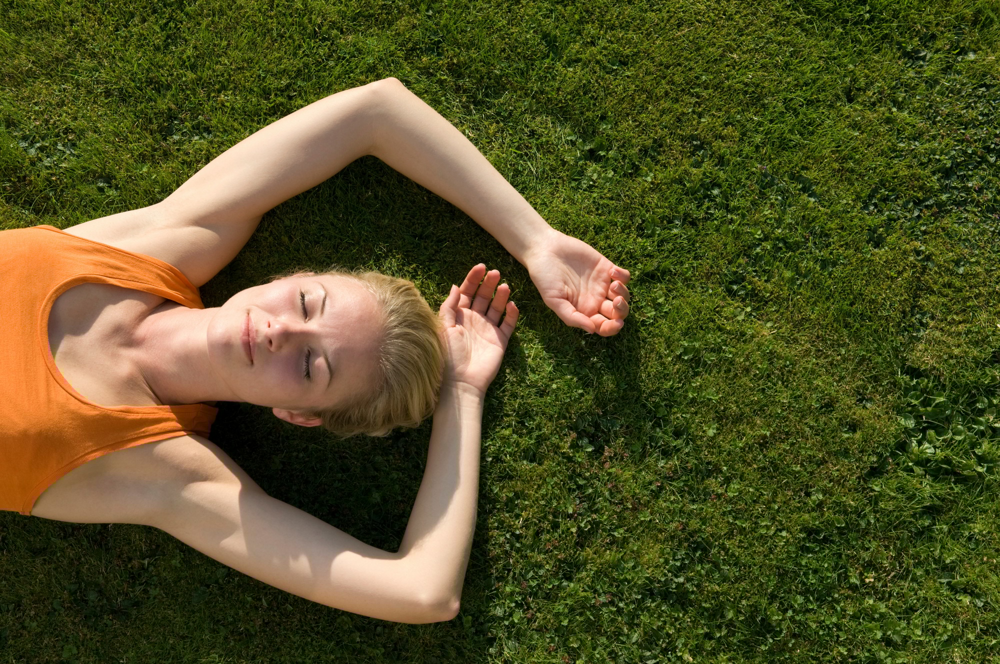 Young person relaxing on a sunny grass field.