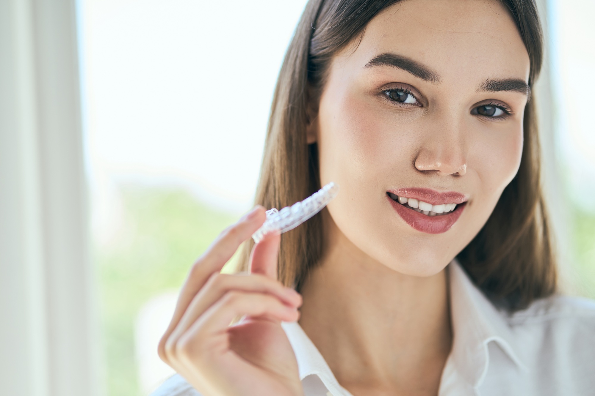 Woman Holding Clear Aligners for Teeth Straightening
